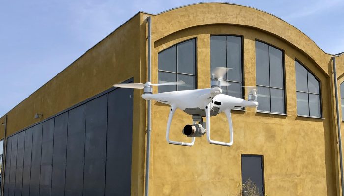 Flyvende drone foran gul bygning. Taginspektion med drone.